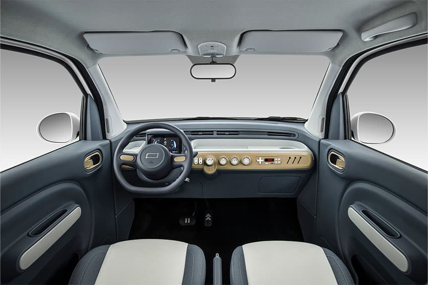 Interior minimalista de un coche eléctrico con tablero gris, detalles dorados y asientos bitono.