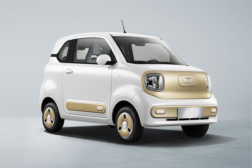 Pequeño coche eléctrico blanco con elegantes detalles dorados en el frontal, puertas y ruedas.